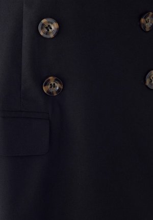 Zwarte stof met vier donkere schildpadknopen gerangschikt in een dubbelgeknoopte stijl en een kleine rechthoekige zak aan de linkerkant.