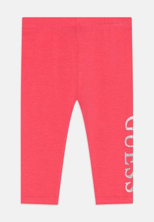 Koraalkleurige legging van zachte katoen, met een glanzende zilveren "GUESS" print op het rechterbeen en een elastische tailleband.