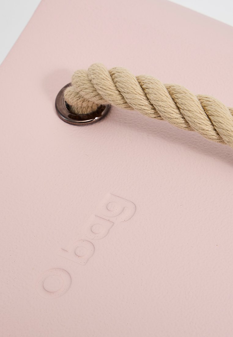 Różowa syntetyczna torba tote o teksturowanym wykończeniu, z beżowym sznurkiem i metalowym oczkiem, wytłoczone logo marki z przodu.