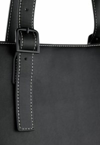 Borsa tote in pelle nera con superficie testurizzata, caratterizzata da cuciture bianche a contrasto e una fibbia nera opaca sulla tracolla.