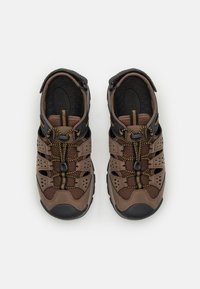 Scarpe in rete marrone e sintetico con accenti neri, suole in gomma e un sistema di allacciatura con cordini elasticizzati. Presentano lati perforati per la traspirabilità.