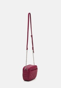 Borsa a tracolla trapuntata bordeaux con dettagli in catena argentata, dotata di chiusura con zip e tracolla regolabile. Forma rettangolare compatta.