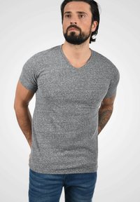 Grå v-hals t-skjorte i en melert tekstur, kortermet og med en tettsittende design, parret med blå jeans.
