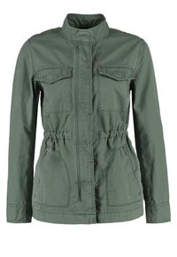 Oliwkowa kurtka wykonana z lekkiego materiału, z kołnierzem stójkowym, dwiema kieszeniami na piersi, ściąganym w pasie oraz bocznymi kieszeniami na zamek.