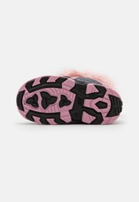 Semelle de baskets noire et rose avec un motif en caoutchouc texturé ; présente des accents roses et un détail velu rose en haut.