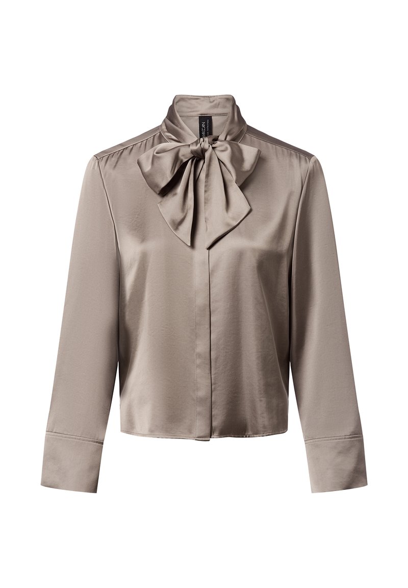 Licht taupe satijnen blouse met een hoge kraag en een groot strikdetail bij de hals. Lange mouwen met knoopmanchetten; gladde, elegante textuur.