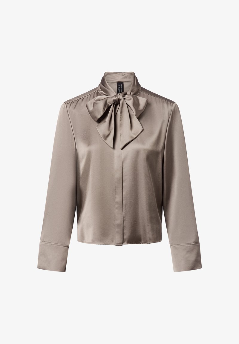 Licht taupe satijnen blouse met een hoge kraag en een groot strikdetail bij de hals. Lange mouwen met knoopmanchetten; gladde, elegante textuur.