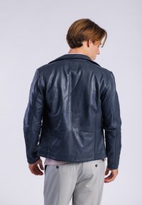 Chaqueta de cuero marina con solapa clásica, corte ajustado y detalles en las costuras. La vista trasera muestra una textura suave y un mínimo de marca.