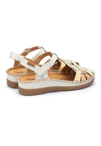 Sandalias de cuero con una combinación de colores beige y marrón, parte superior trenzada, correas ajustables y suela plana de goma con costuras decorativas.