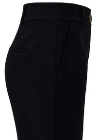 Pantalones negros a medida con bolsillos laterales, trabillas para cinturón y un pequeño detalle de botón en la cintura.