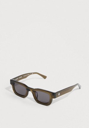 Pravokotna sončna očala z rjavim prosojnim okvirjem, temnimi lečami in srebrnimi poudarki na stranici; ročno izdelana v Vietnamu.