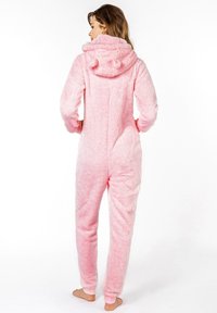 Roze zachte onesie met een capuchon met berenoren, lange mouwen en elastische manchetten. Zachte textuur en een relaxed fit. Geen zichtbare sluitingen.