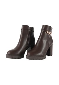 Stivali alla caviglia in pelle marrone con zip laterale, tacco spesso e dettaglio in catena alla caviglia. Suola testurizzata per una migliore aderenza.