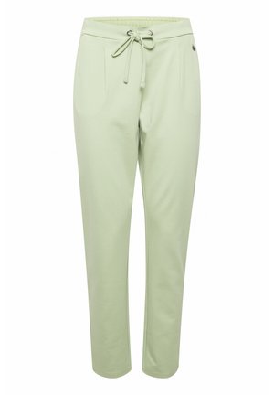 Světle zelené tepláky s nastavitelným páskem, obsahující dvě boční kapsy a hladkou, mírně strukturovanou látku.