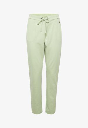 Světle zelené tepláky s nastavitelným páskem, obsahující dvě boční kapsy a hladkou, mírně strukturovanou látku.