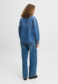 Denim jacket and matching wide-leg jeans in medium blue. Features include a relaxed fit, visible stitching, and button accents on the sleeves.