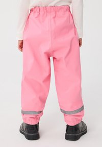 Różowe wodoodporne spodnie z elastycznym paskiem w talii i mankietami na kostkach. Odblaskowy pasek na dole nogawek. Gładka, błyszcząca tekstura.