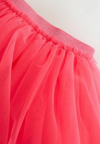 Falda de tul rosa con cinturilla elástica fruncida. La tela es ligera y translúcida, con una textura suave y aireada y un acabado brillante.