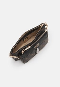 Pochette Guess noire et marron avec fermetures éclair dorées, intérieur beige et motif logo, partiellement ouverte montrant les compartiments intérieurs et l'étiquette de la marque.