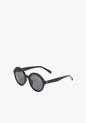 Lunettes de soleil noires avec des montures rondes, des verres teintés foncés et des branches noires élégantes avec un fin accent métallique reliant la monture et les branches.