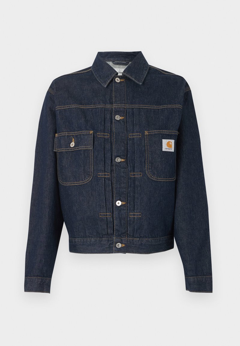 Dunkelblaue Jeansjacke mit Knopfleiste, zwei Brusttaschen – eine mit Knopflappe, die andere mit einem kleinen Etikett auf der rechten Tasche.