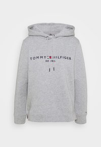 Ljusgrå Tommy Hilfiger hoodie med framsidan logotyp, "Tommy Hilfiger EST 1985", dragskohuva och ribbade muddar och nederkant.