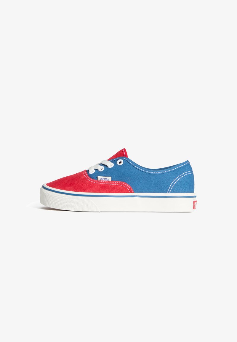 Baskets en toile rouge et bleue avec des lacets blancs, une semelle en caoutchouc et des surpiqûres contrastées. Présente une étiquette avec le logo Vans sur le côté.