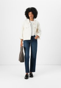 Hvit denimjakke, hvit t-skjorte, mørkeblå rettskårne jeans, svarte loafers, grå tote-veske; minimalistisk design, glatt tekstur, avslappet passform.