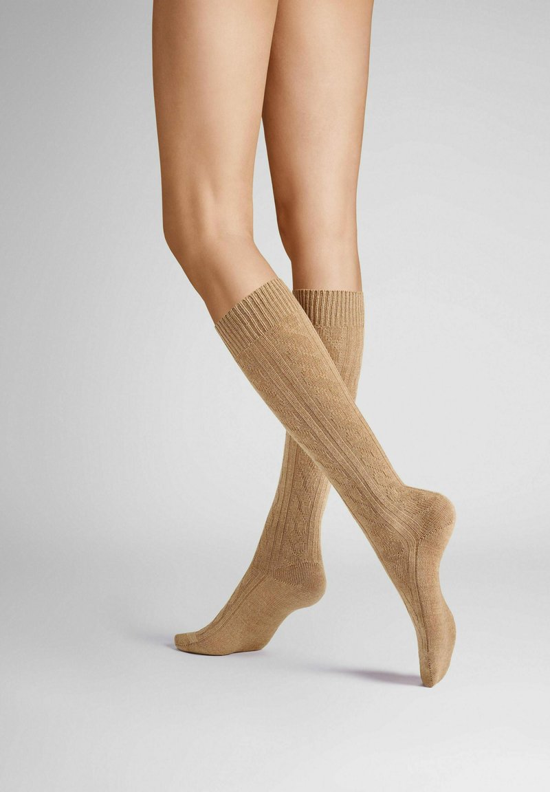 Knee-high socks in beige, featuring a ribbed texture and subtle pattern, with thick ribbed cuffs and a smooth foot section.