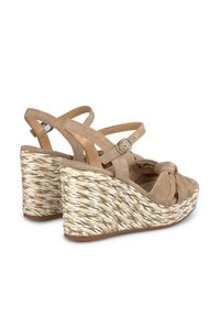 Sandalias de cuña de ante beige con un frente anudado, que cuentan con correas ajustables y una textura trenzada similar al yute en el talón de cuña.