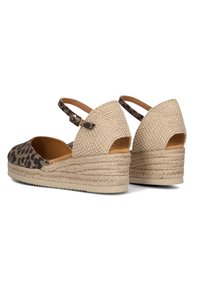 Twee wedge sandalen met een luipaardprint stof aan de voorkant, tan leren voering en een geweven jute hak, voorzien van een gesp enkelbandje en een open achterkant ontwerp.