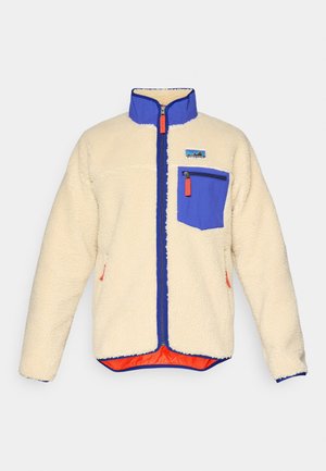 Cream fleece jacket with blue collar, blue zippered chest pocket, blue zipper trim, and orange zipper pulls, visible brand patch on chest.