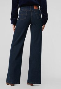 Széles szárú, sötétkék farmernadrág farmer anyagból. Látható varrásokkal, két hátsó zsebbel és márkajelzéses derékpánttal.