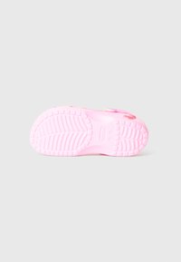 Semelle en caoutchouc rose de sabot avec un motif de grip texturé et un logo en relief, dotée d'un léger talon et de bords arrondis.