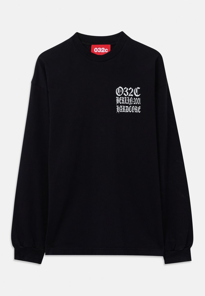 Chemise noire à manches longues avec un texte gothique blanc "032C BERLIN:2001 HARDCORE" sur la poitrine gauche et une étiquette de marque rouge à l'intérieur du col.