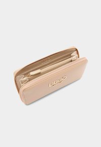 Leren portemonnee in zacht beige met gouden ritsen, een gestructureerde afwerking, meerdere vakken en een reliëflogo aan de voorkant.