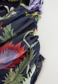 Blommigt mönstrad tyg i marinblått, med röda och gröna blad. Lätt, strukturerat material med sammetskanter och mjuk fall.