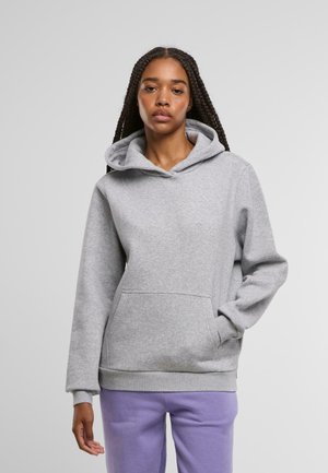 Szürke kapucnis pulóver puha anyagból, kanguru zsebbel, bordás mandzsettákkal és laza szabással. Lila nadrággal viselve.