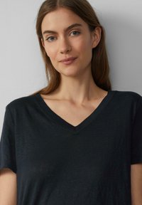 Zwarte V-hals t-shirt met korte mouwen, gemaakt van een zachte, lichte stof. Heeft een ontspannen pasvorm en een subtiele textuur.