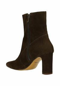 Bottines en suède marron avec un bout pointu, fermeture éclair latérale et un talon bloc. Les coutures soulignent la structure. Doublure intérieure lisse.
