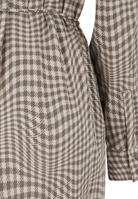 Brown and beige houndstooth patterned dress with a belted waist, featuring a collared neckline and buttoned cuff accents.