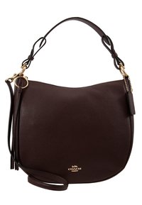 Sac à épaule Coach en cuir marron foncé avec quincaillerie dorée, double sangle, fermeture éclair et petit détail pompon.