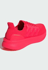 Helles pinkes Laufschuh mit einer strukturierten Strickoberfläche, drei auffälligen Seitenstreifen und einer gedämpften Sohle. Mit "ULTRABOOST"-Markenkennzeichnung.