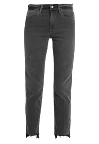 Jeans de mezclilla negra con un diseño ajustado, que presentan dobladillos deshilachados y un estilo clásico de cinco bolsillos. La tela tiene una textura suave.