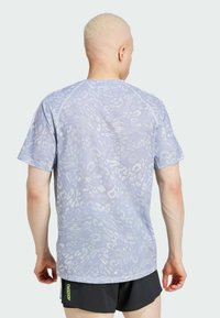 Ljusblå mesh idrottströja med ett subtilt mönster, korta ärmar och avslappnad passform, som är kombinerad med svarta shorts med en logotyp.