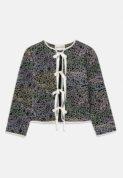 Zöld, kék és sárga virágmintás kardigán fekete háttérrel, fehér masni záródással és hosszú ujjakkal.