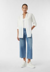 White button-up shirt, light blue denim wide-leg jeans, and white sneakers. Short sleeves and relaxed fit with front buttons.