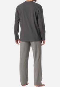 Haut à manches longues gris en matériau doux, associé à un pantalon gris clair avec un motif subtil. Le pantalon a une taille élastique.