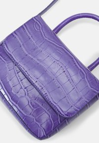 Fioletowa torba z ekoskóry o fakturze w zamek krokodyla, z zamknięciem na klapkę i smukłym paskiem na ramię.