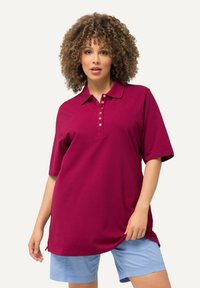 Burgundské polo tričko s krátkým rukávem, se zapínáním na knoflíky a volným střihem, spárované s světlomodrými šortkami. Hladký bavlněný materiál.